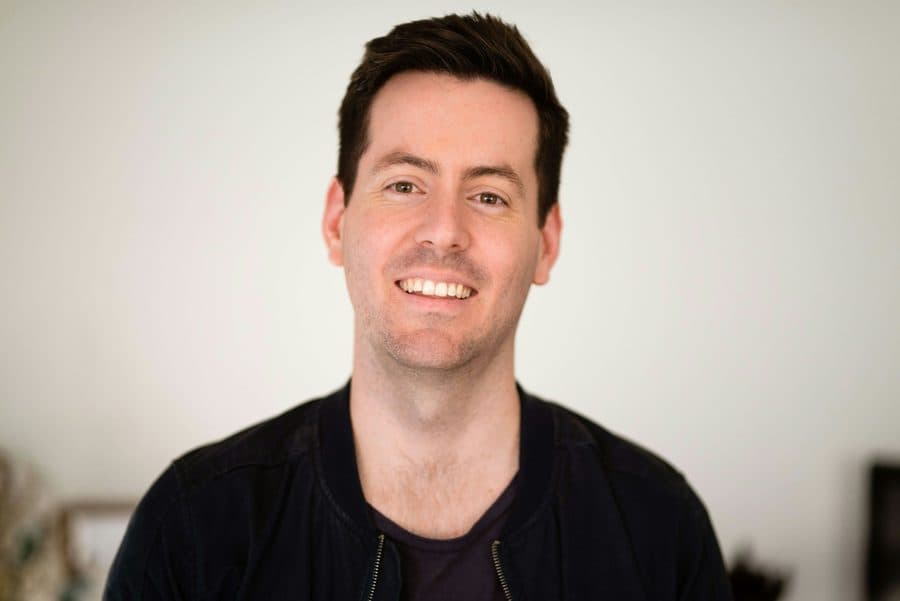 Portrait of Dr Tom Whitcombe, a dentist with short dark hair, smiling