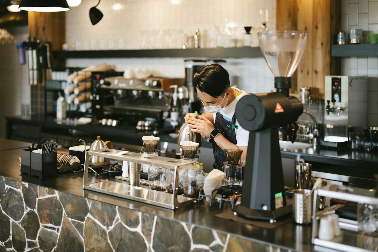 A barista working at the espresso machine behind a busy café counter