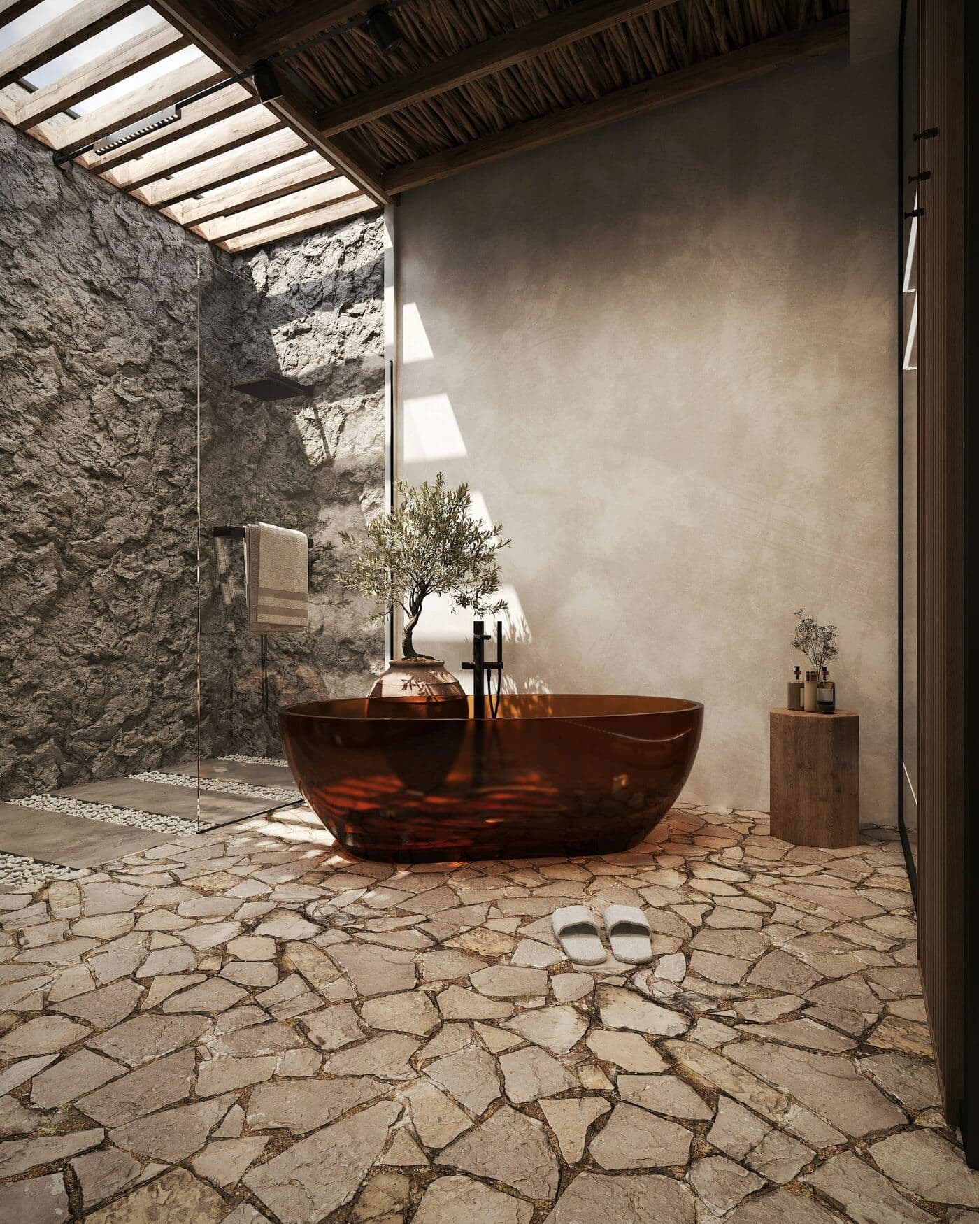 An amber glass freestanding bath in a room of rough stone walls and flagstone floor, lit by a skylight