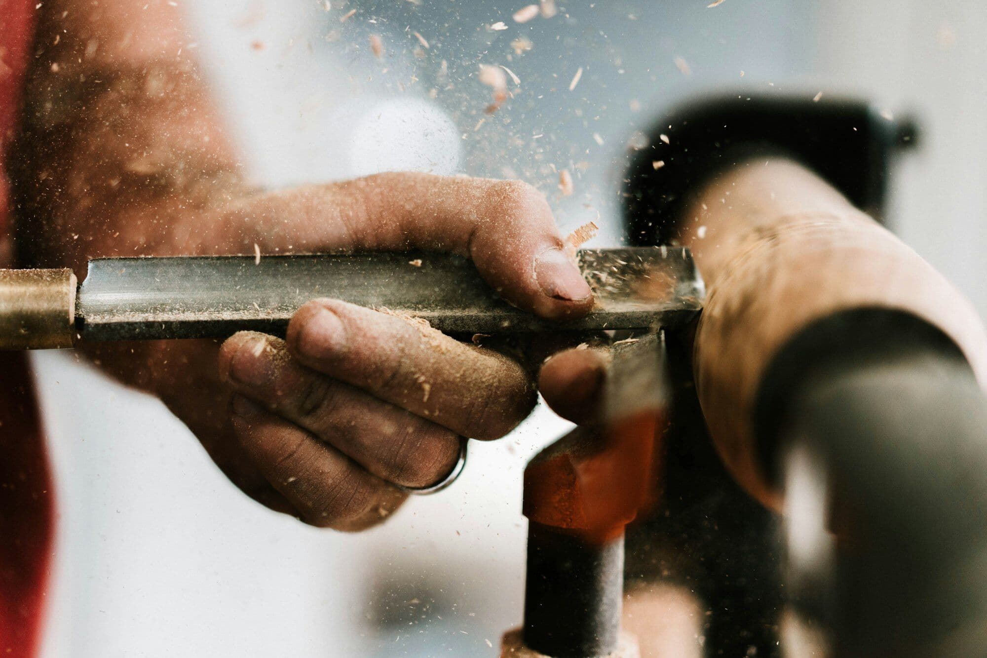 A plumber’s hands cutting copper pipe, sparks caught in warm light