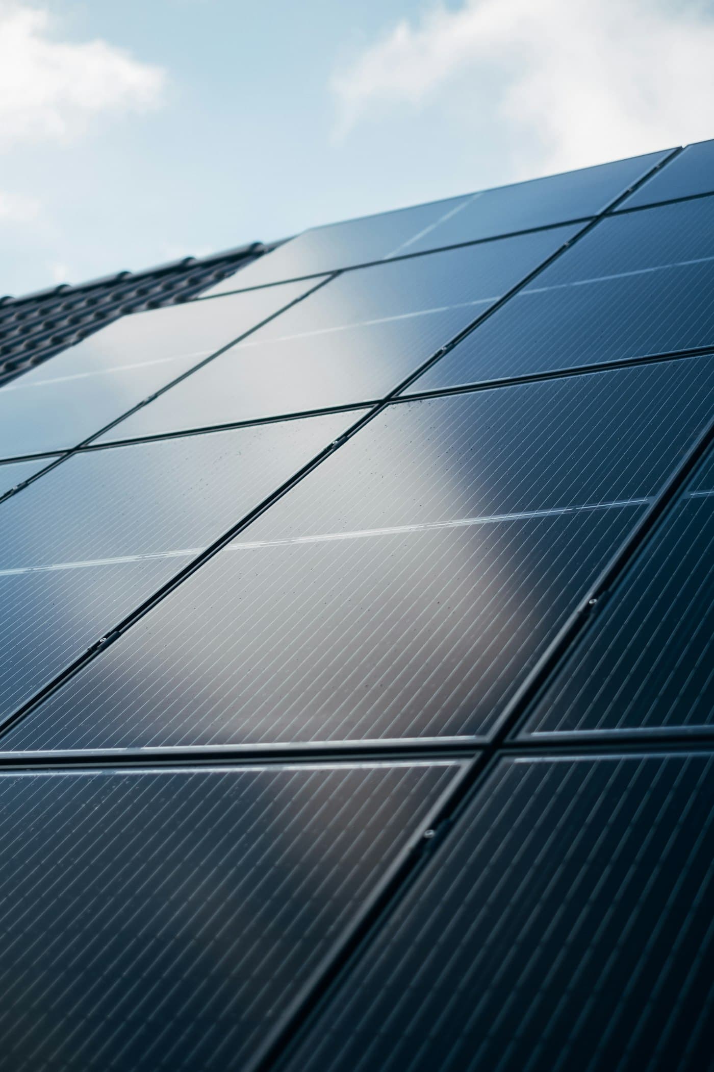 Close-up of dark solar cells reflecting a blue sky
