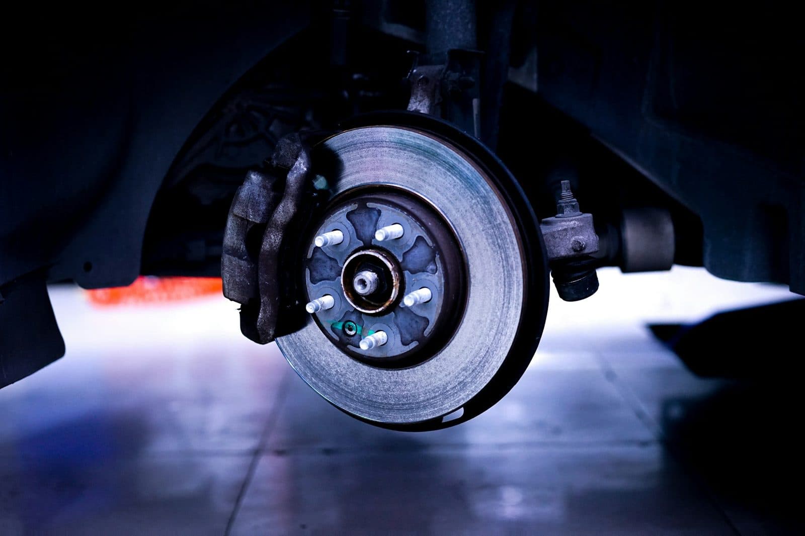 A bare brake disc and caliper on a car with the wheel removed