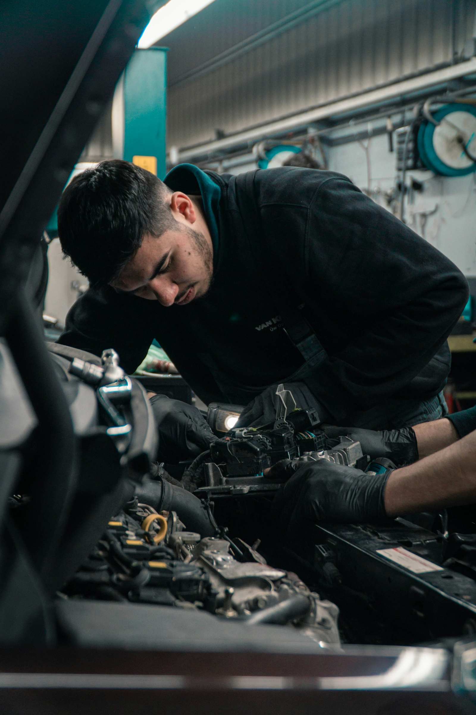A mechanic in gloves working in an open engine bay