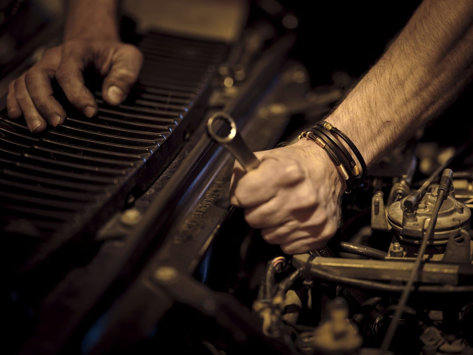 A mechanic's hand turning a spanner inside an engine