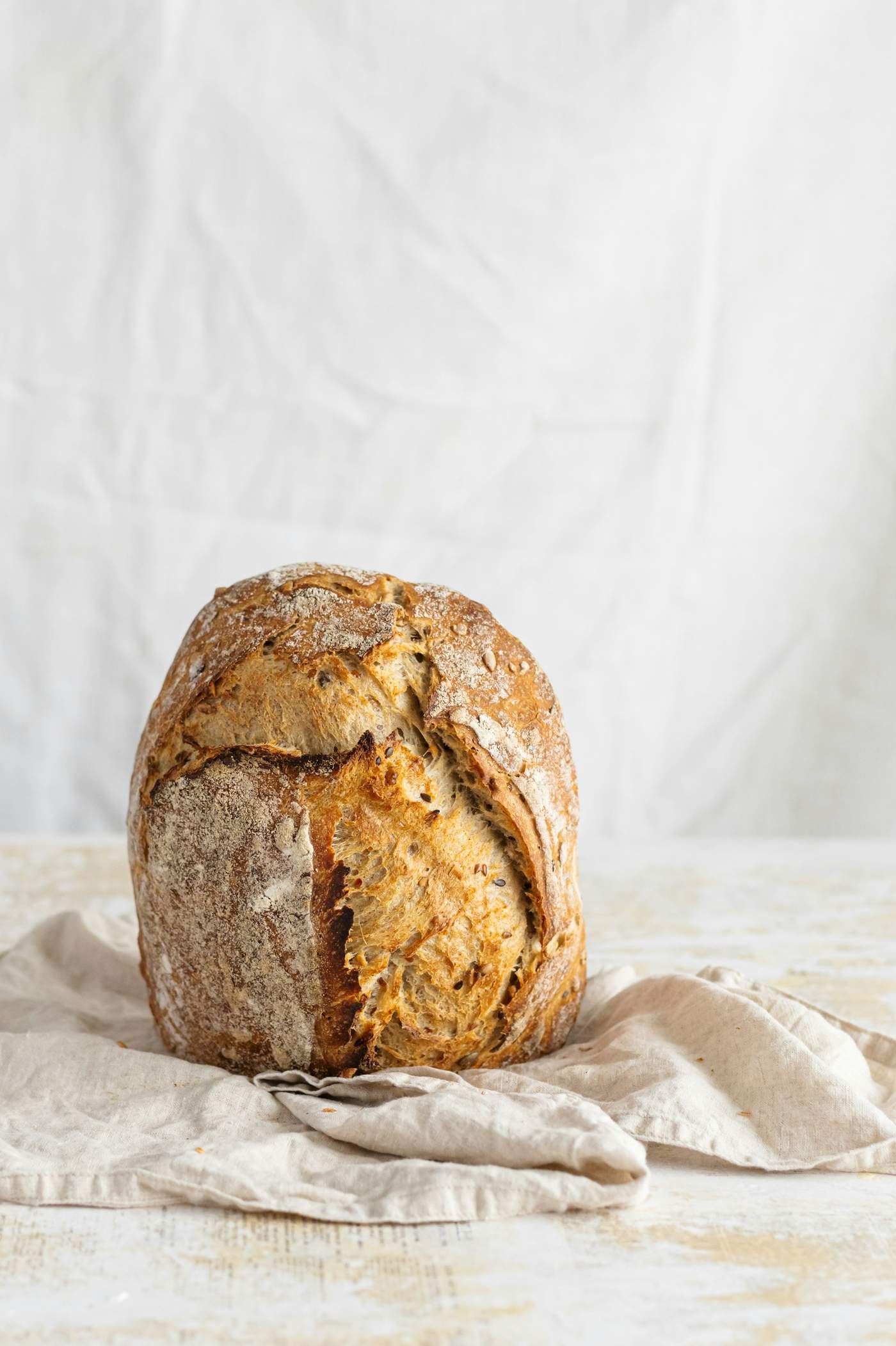 A scored sourdough loaf on a wooden board