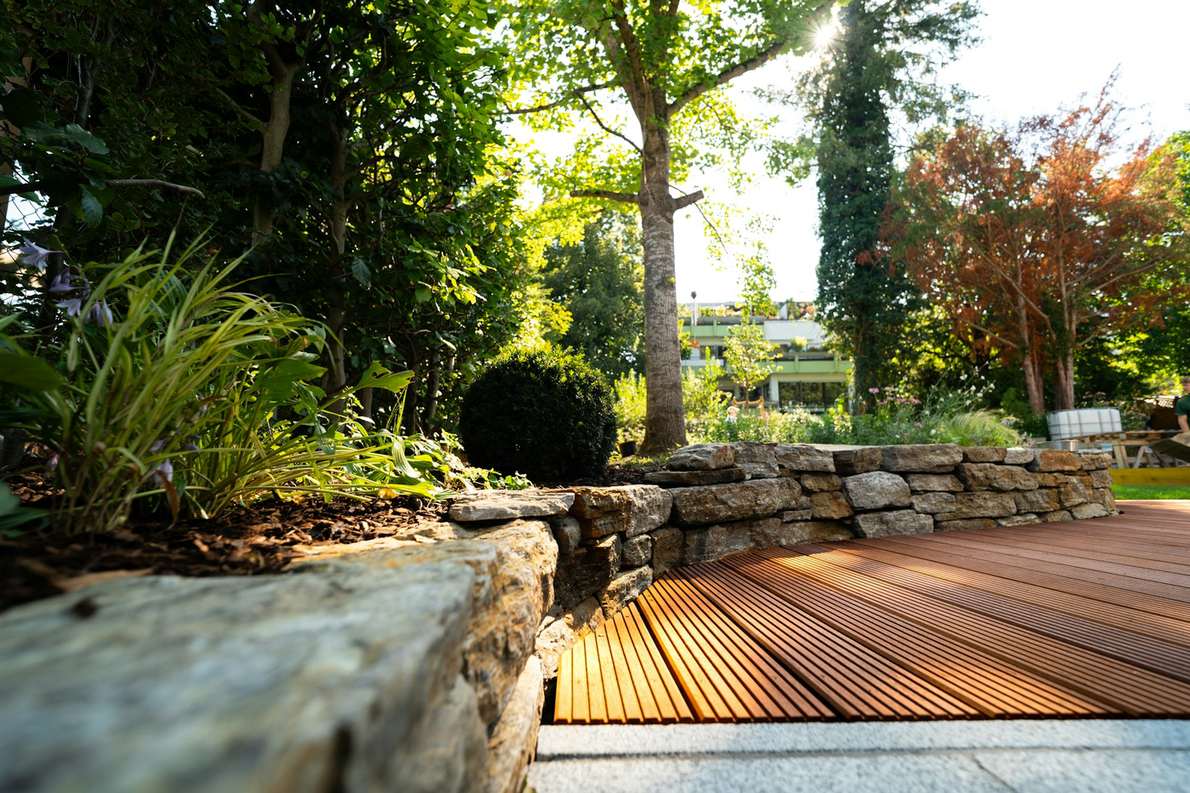 A timber deck edged with a dry-stone wall and mature trees