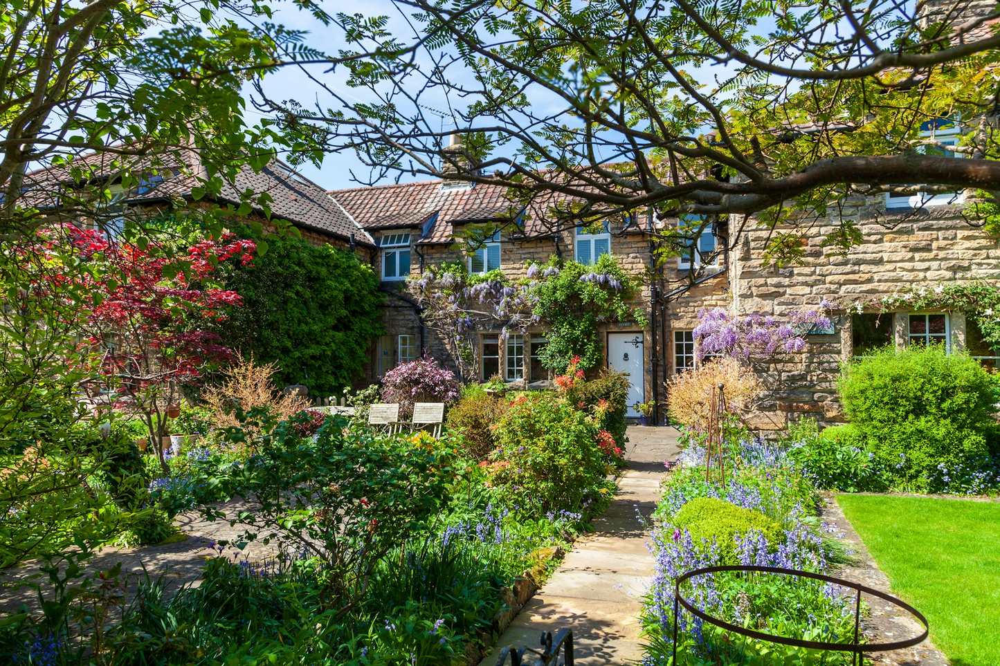 A cottage garden in full flower in front of a stone house