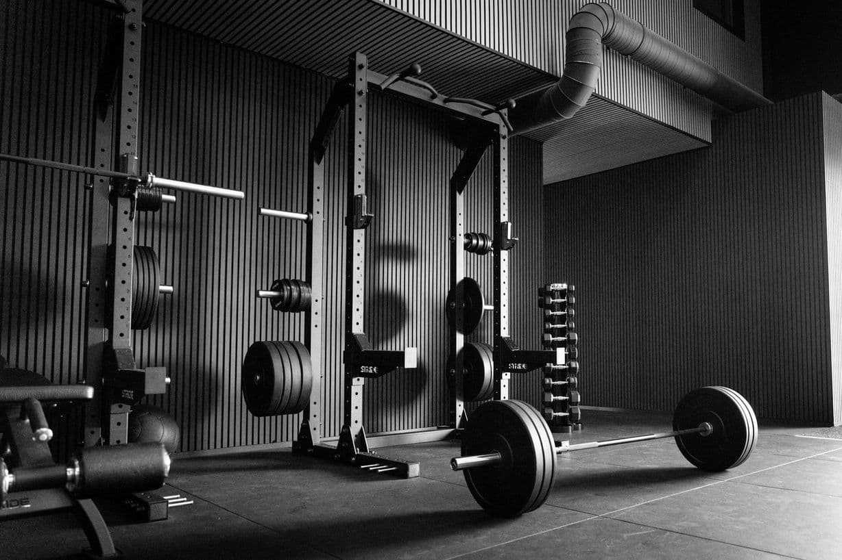 Two power racks with barbells and plates in a clean corner of the gym