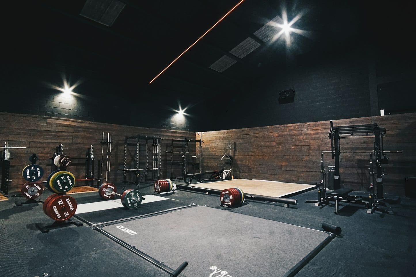 The gym floor: lifting platforms, racks and bumper plates against a brick wall