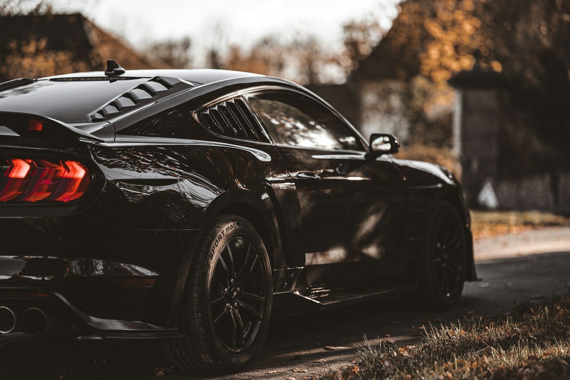 After: a black coupé with deep, mirror-like paint reflecting autumn trees