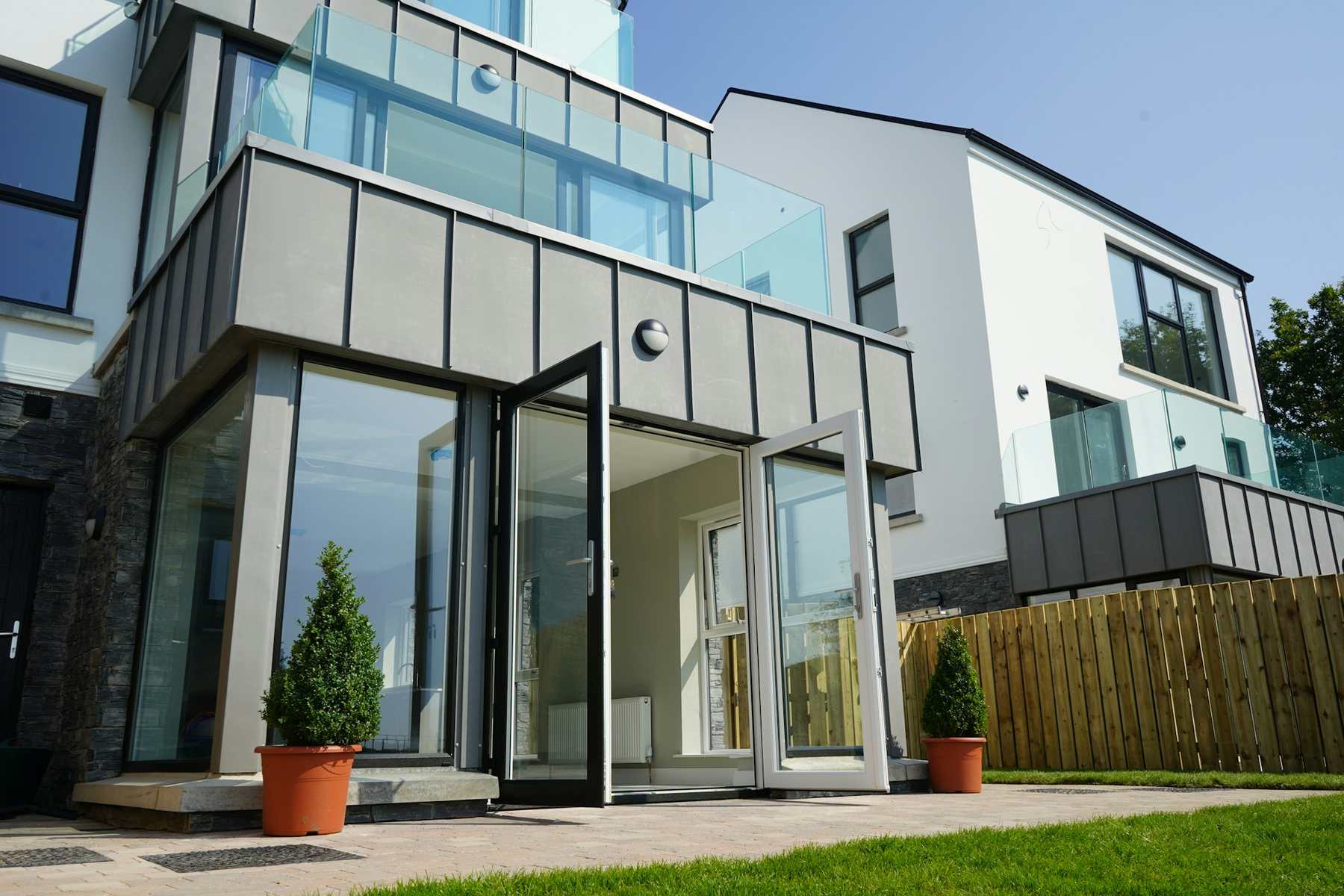 A contemporary glazed rear extension with zinc cladding and open sliding doors onto a lawn