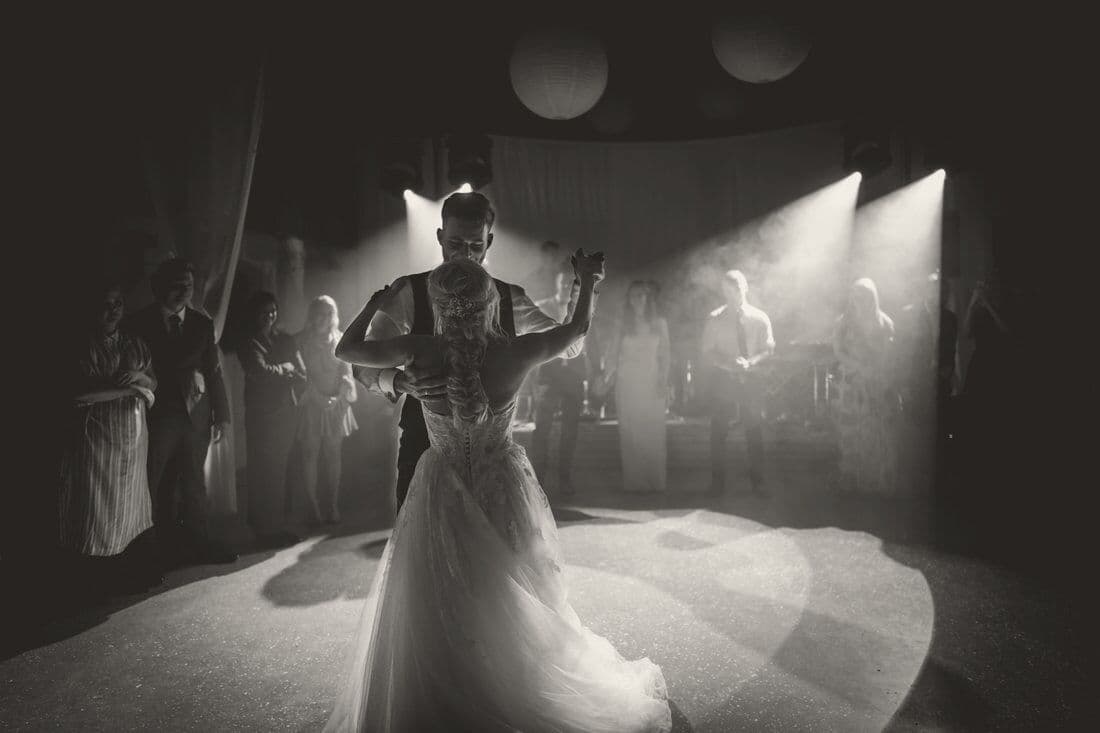 A couple’s first dance under stage lights while guests watch