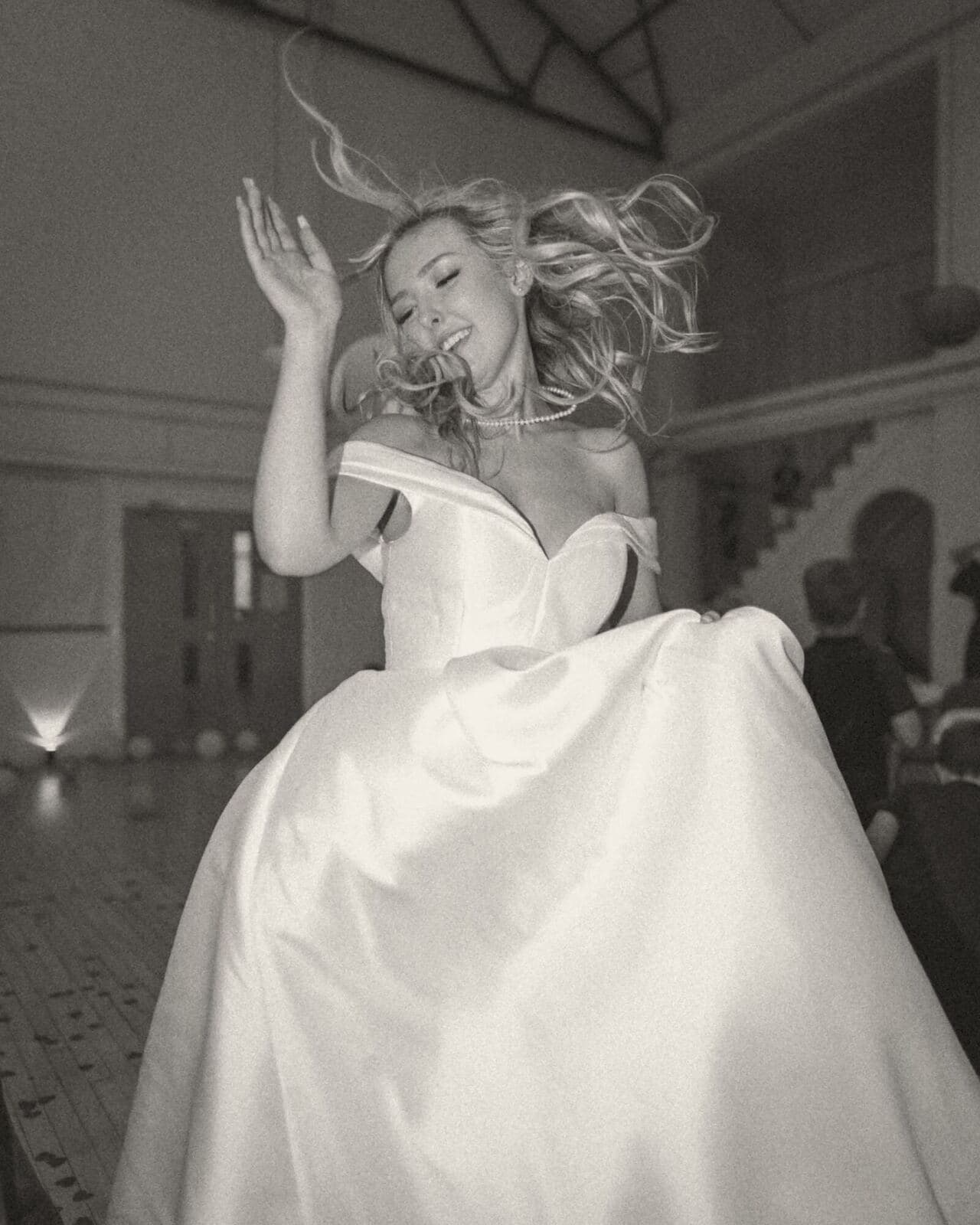 A bride mid-jump on the dance floor, her skirt flaring