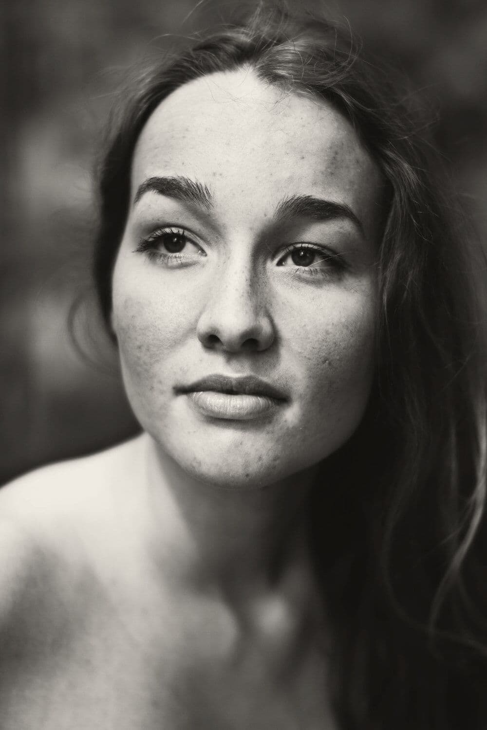 A close portrait of a freckled woman looking just past the camera