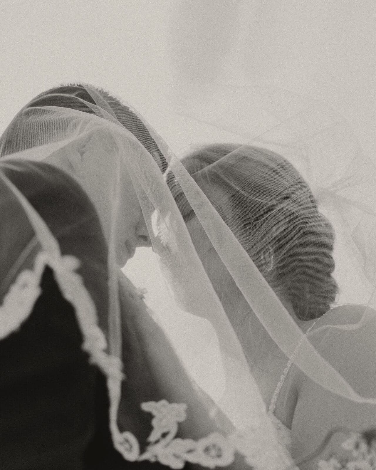 Two faces close together beneath a lace-edged veil