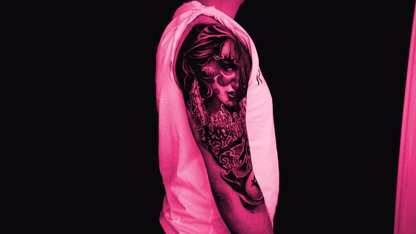 A portrait half-sleeve on an upper arm against a dark ground