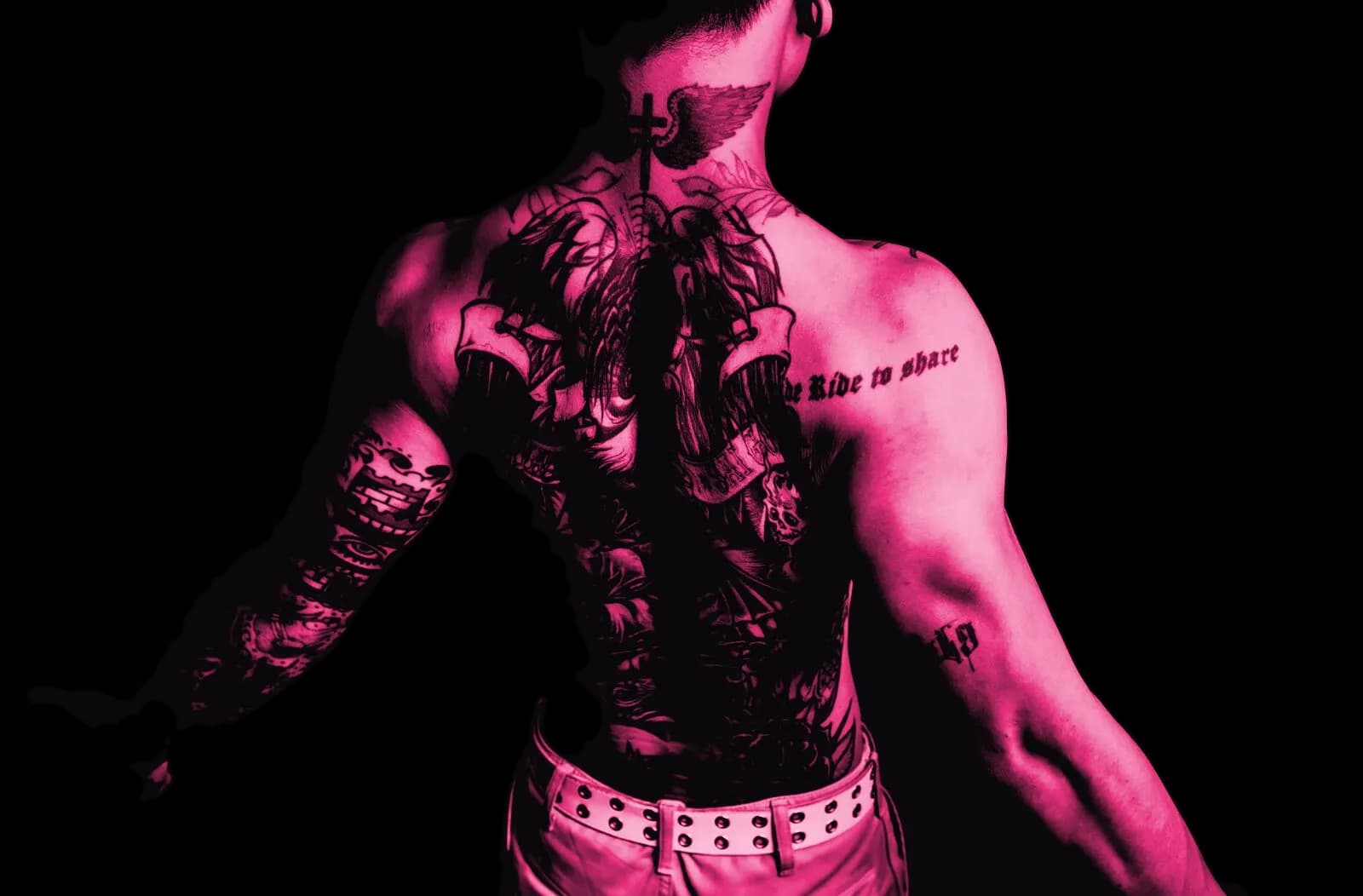 A client's heavily tattooed back and arms, shot from behind in hard pink light