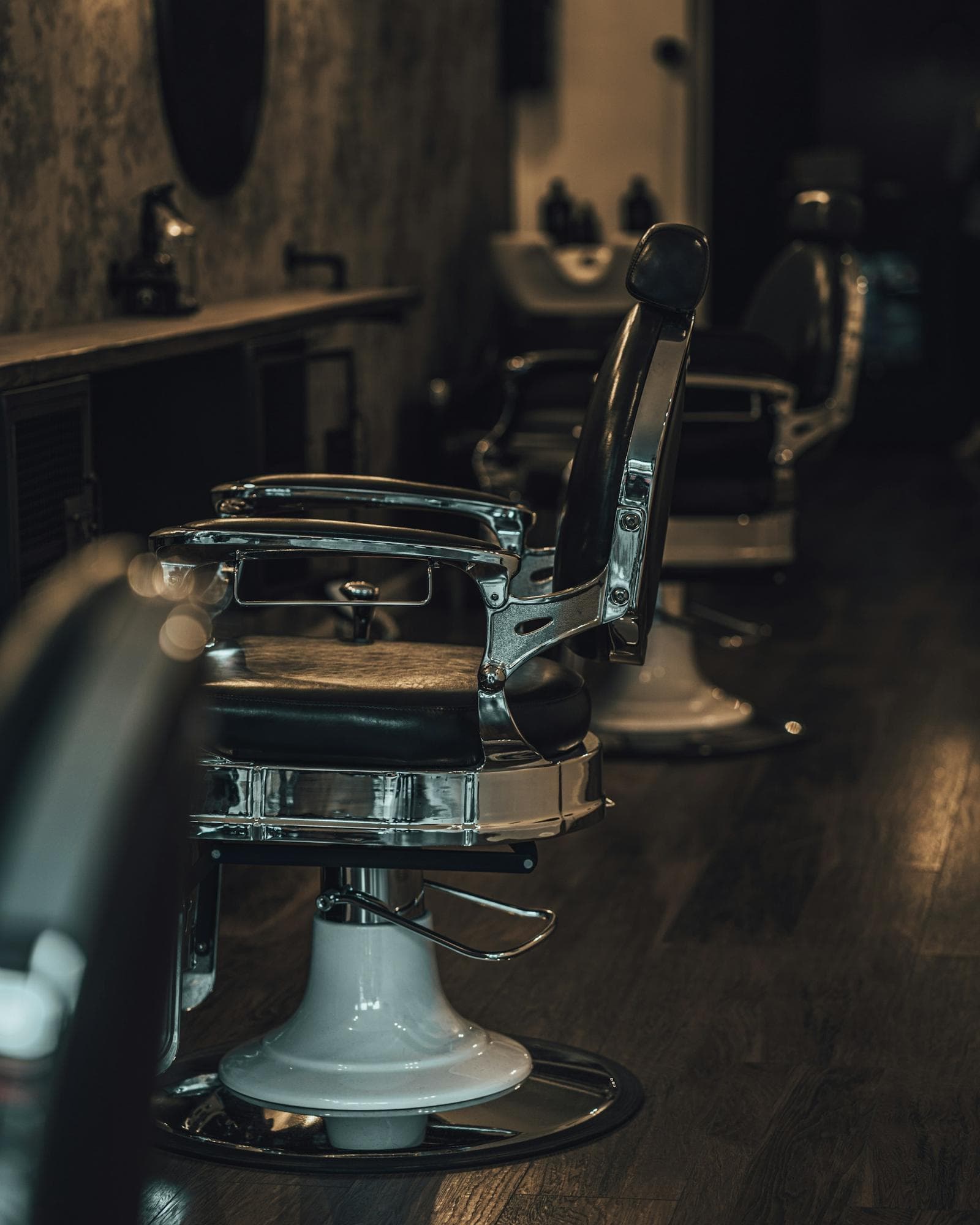 A vintage chrome and leather barber chair in a dim, brick-walled shop