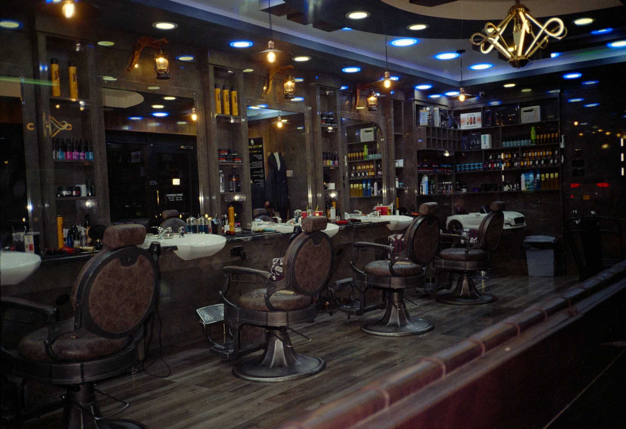 The shop at night: a row of leather barber chairs under warm lights and mirrors