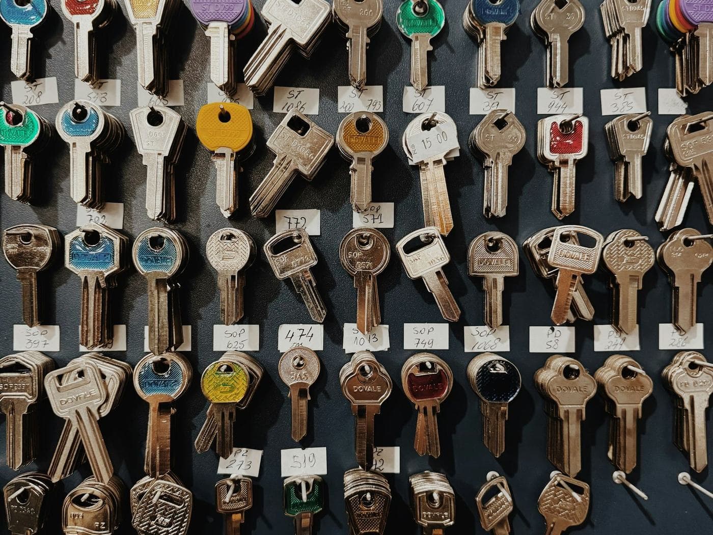 Rows of key blanks hanging on hooks on a workshop wall, each with a handwritten label