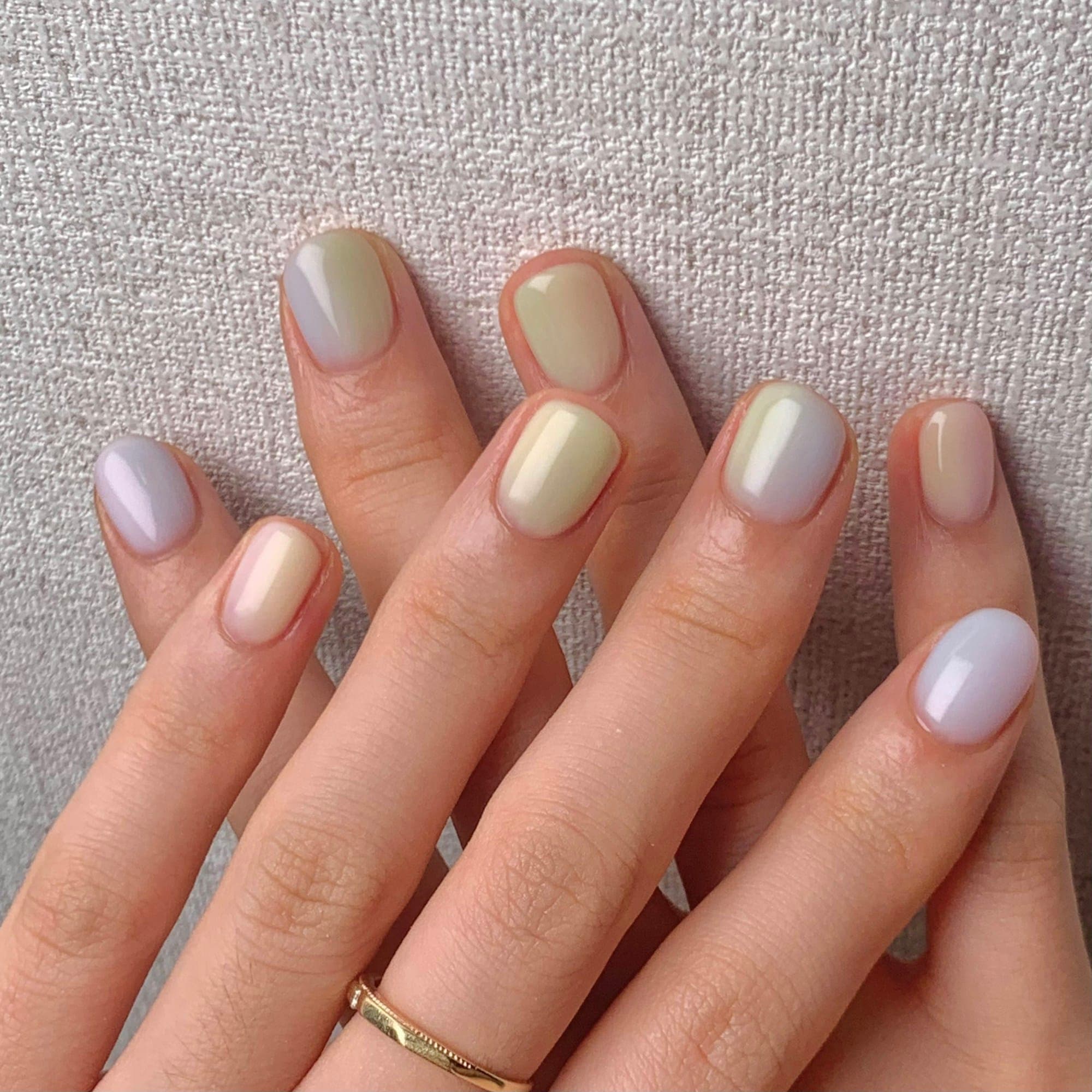Short rounded nails in soft pastel lilac, butter and mint with a pearly finish