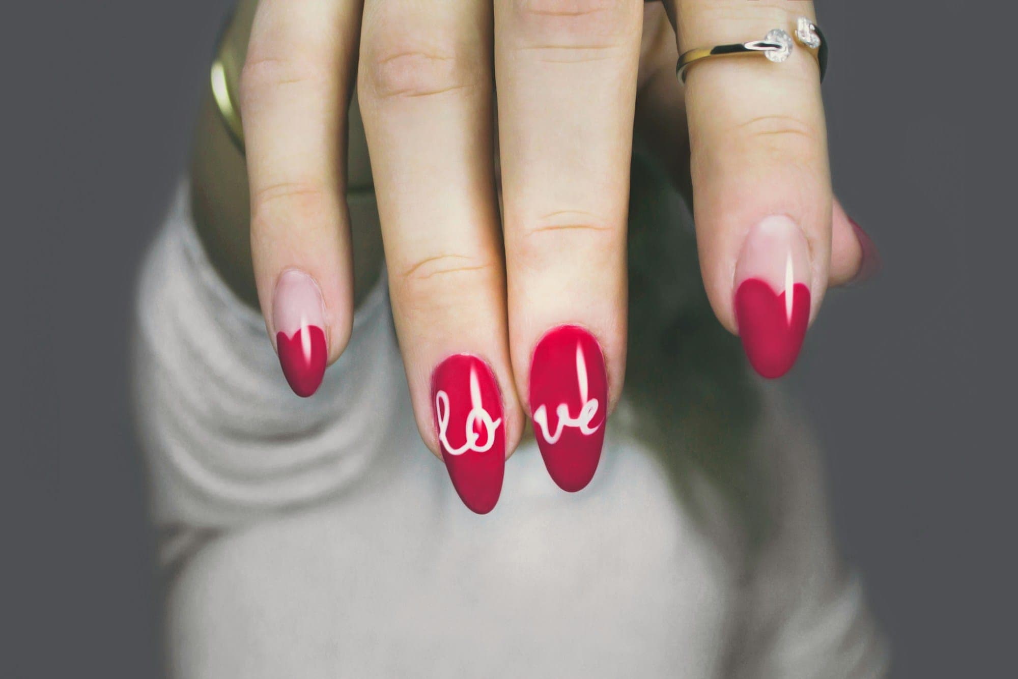 Almond nails in cherry red with the word love hand-painted in white script