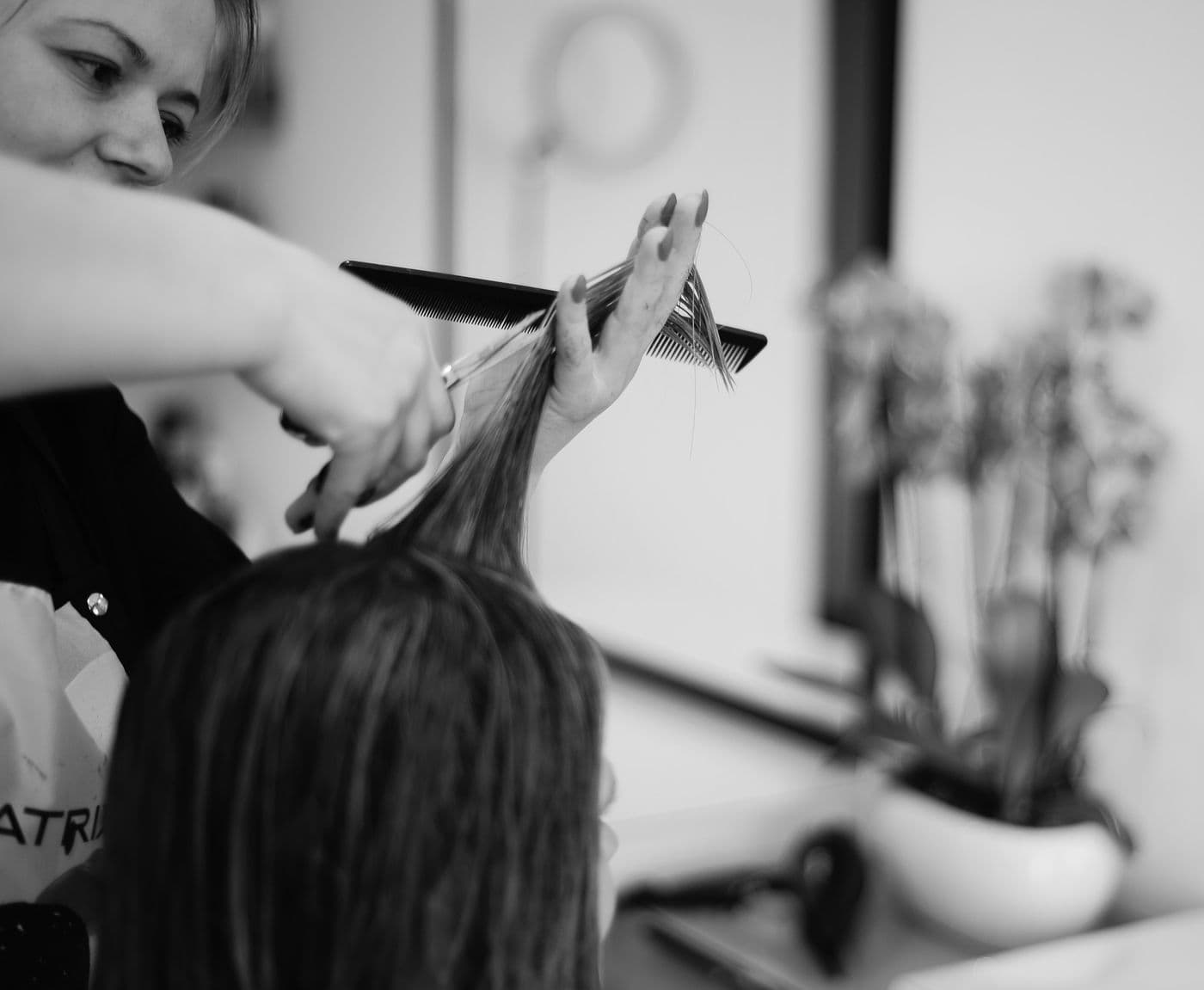 Black and white photo of a stylist sectioning and cutting wet hair