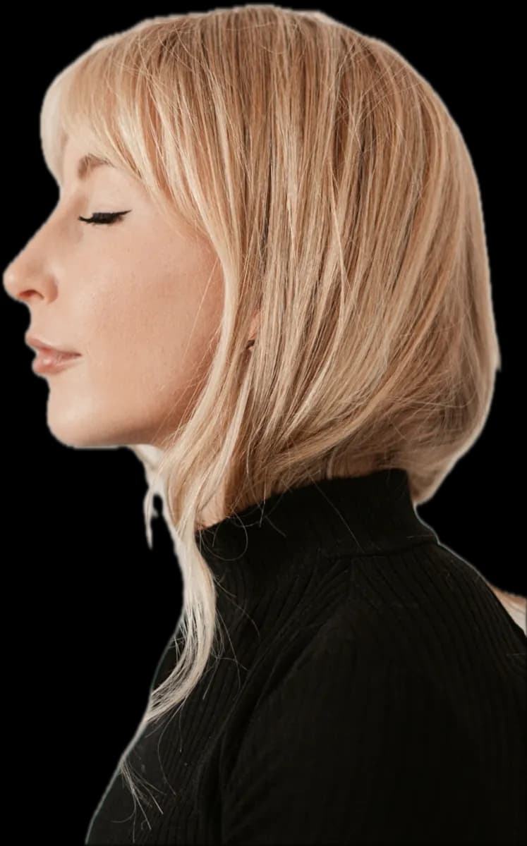 Profile of a woman with a pale blonde, chin-length bob and a curtain fringe, in a black roll-neck