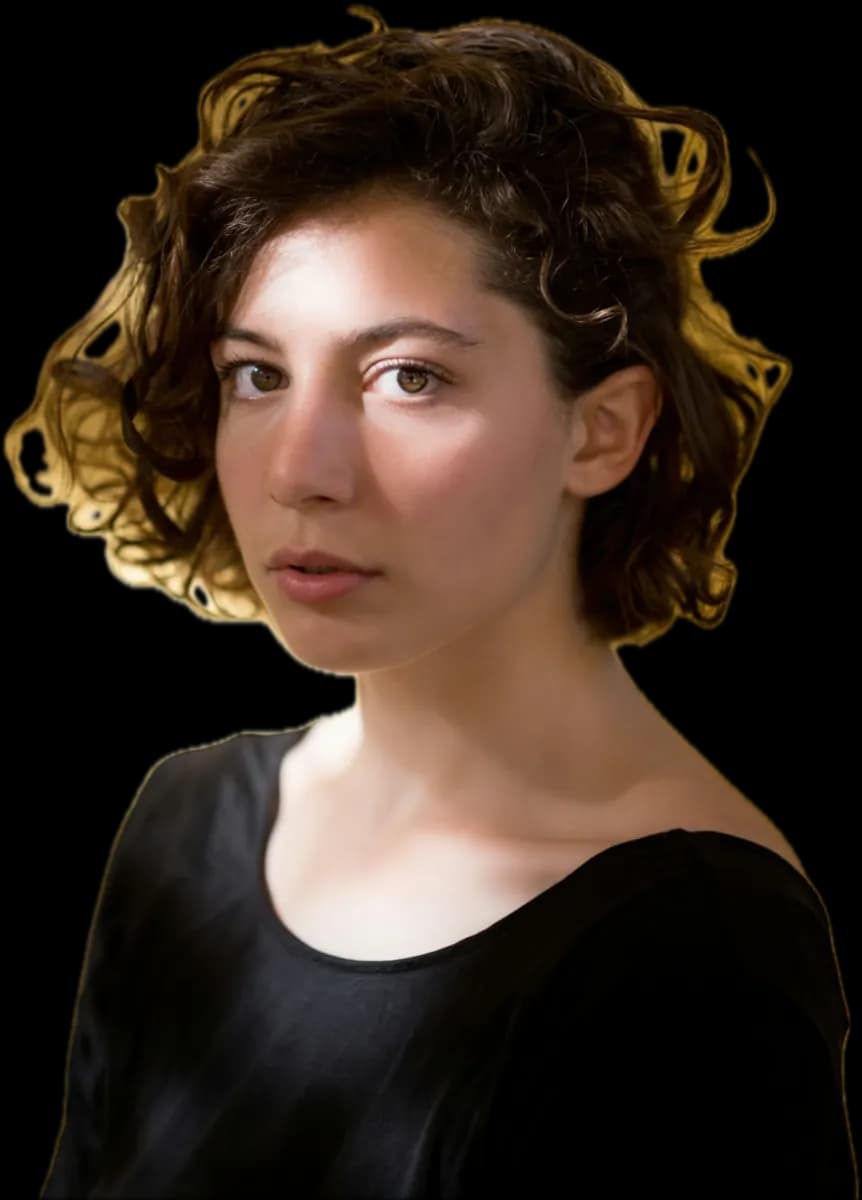 Woman with short, glossy dark curls and a black top, looking into the camera