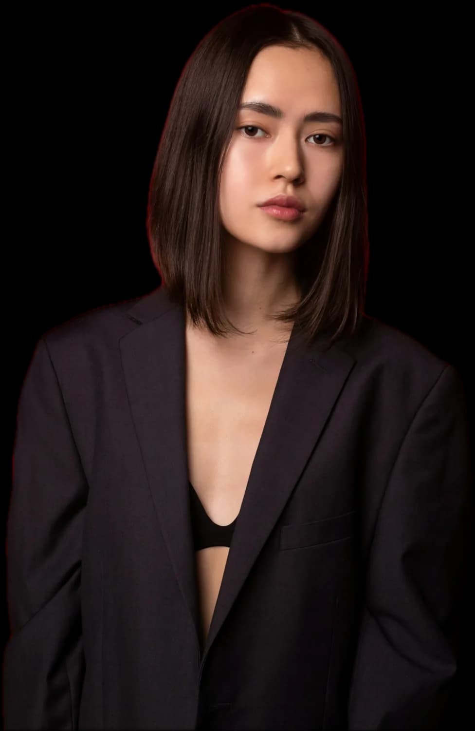Woman with a sleek, glossy dark bob cut to the jaw, in a black blazer