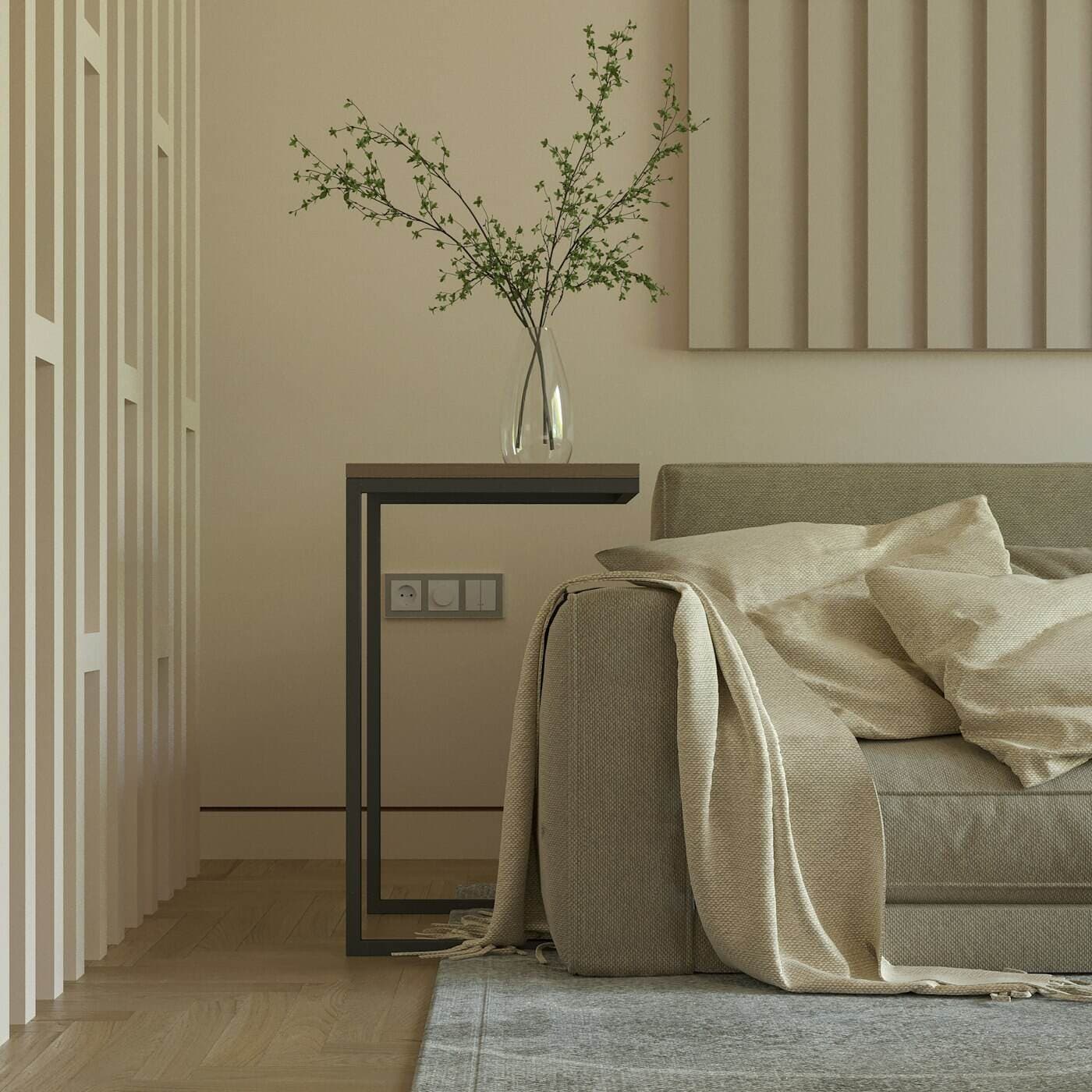 A pale sofa with a draped linen throw beside a slim console and a vase of branches