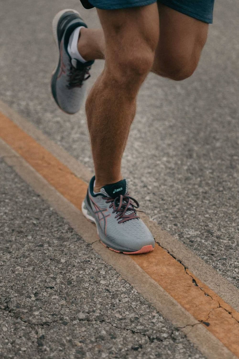 A runner’s legs and trainers mid-stride on a road