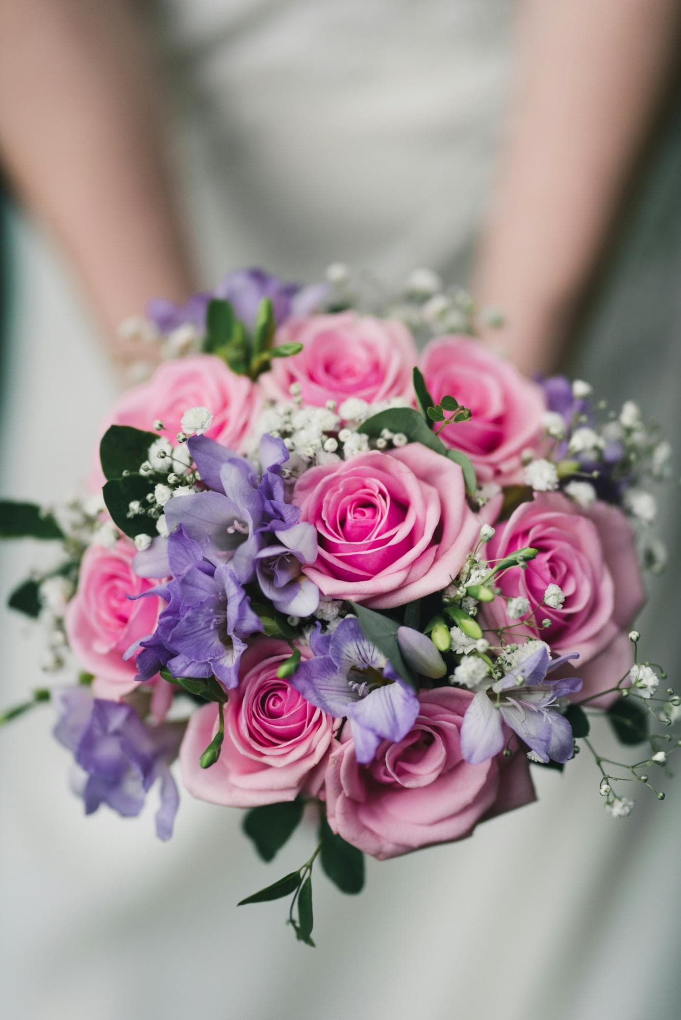 A bride holding a bouquet of pink roses and lilac stocks
