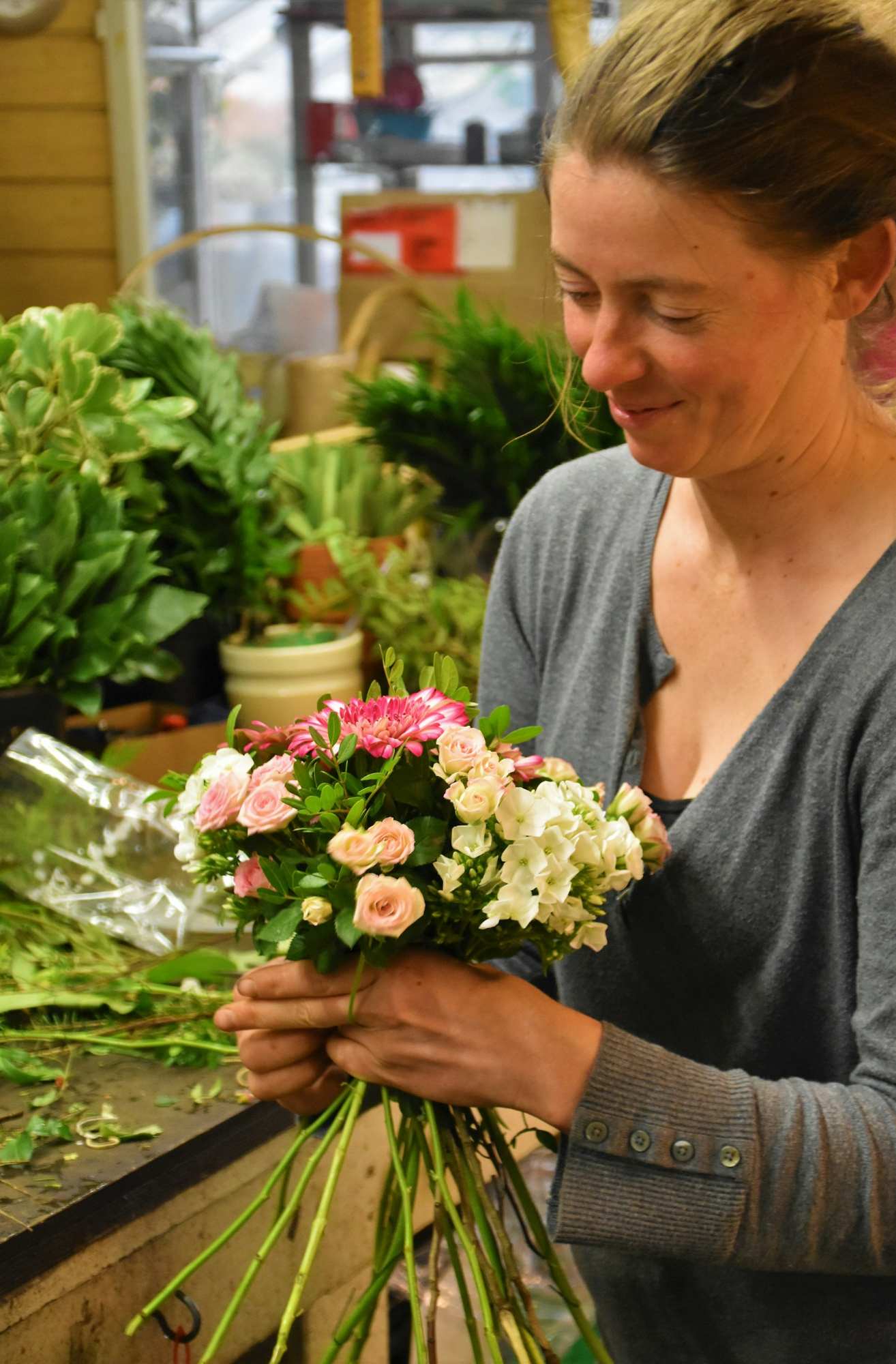 The florist holding a freshly tied bouquet in the shop