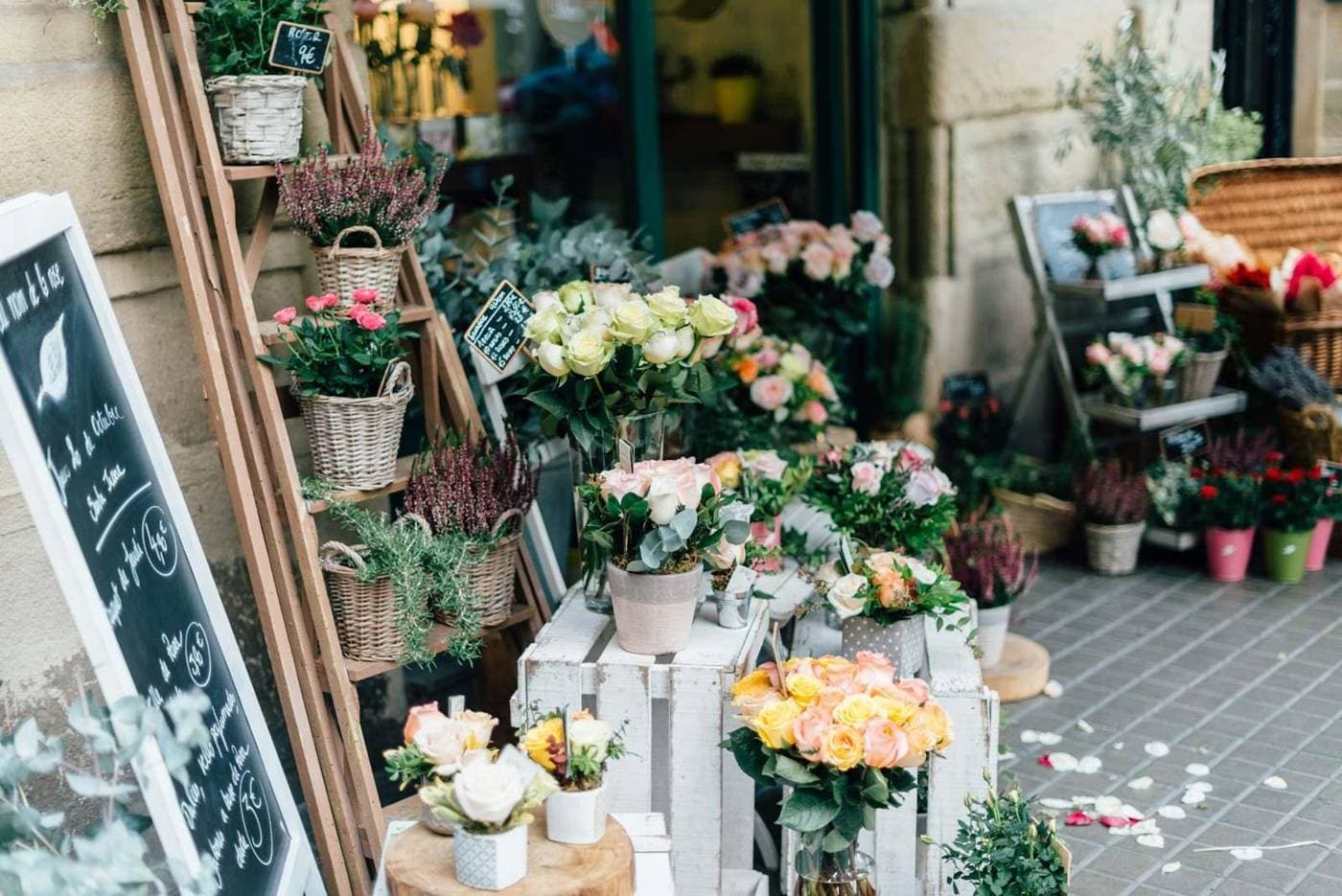 Buckets of roses and heather outside a flower shop, petals on the pavement