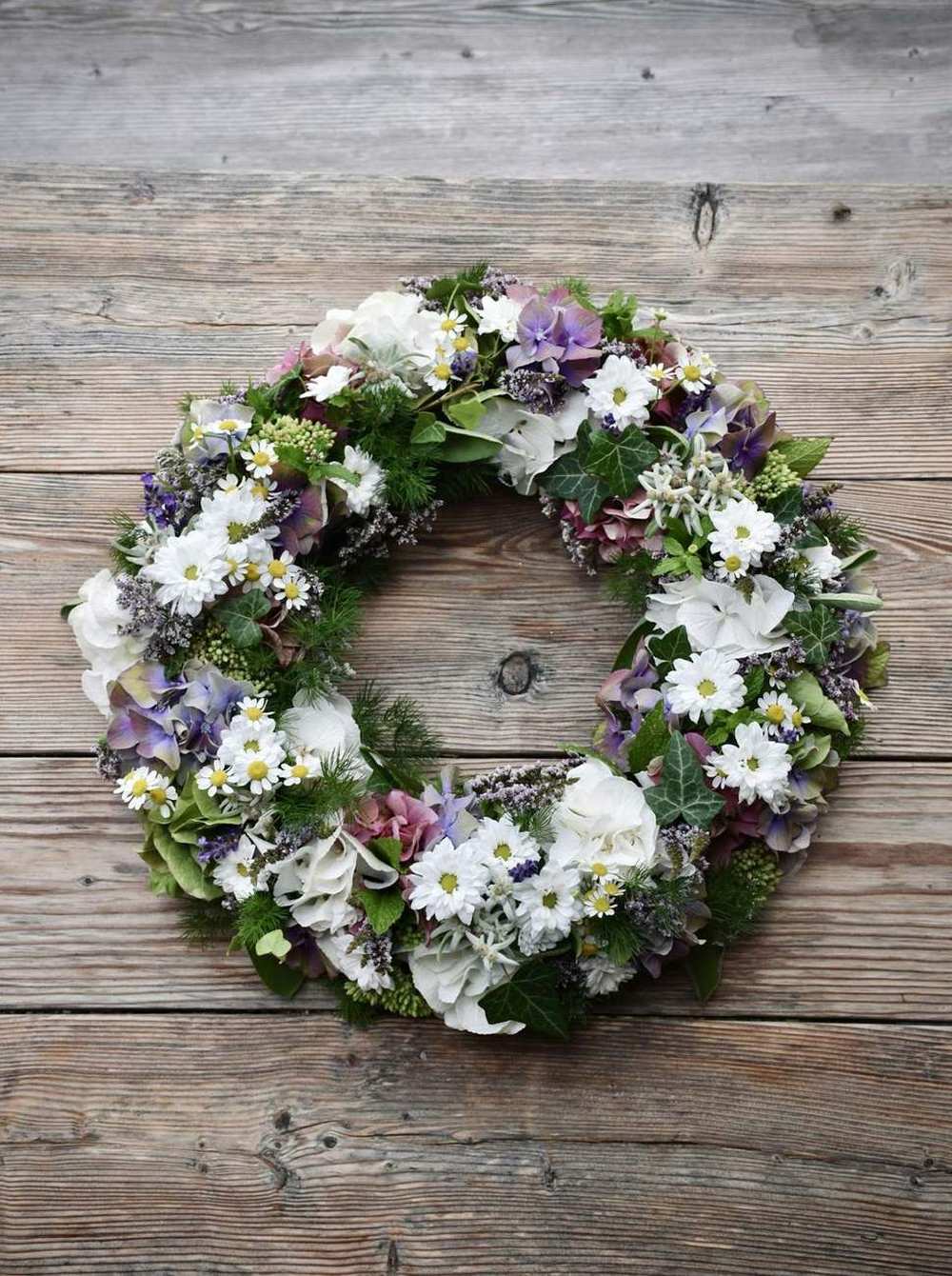 A round funeral wreath of white roses, lilac and soft greenery