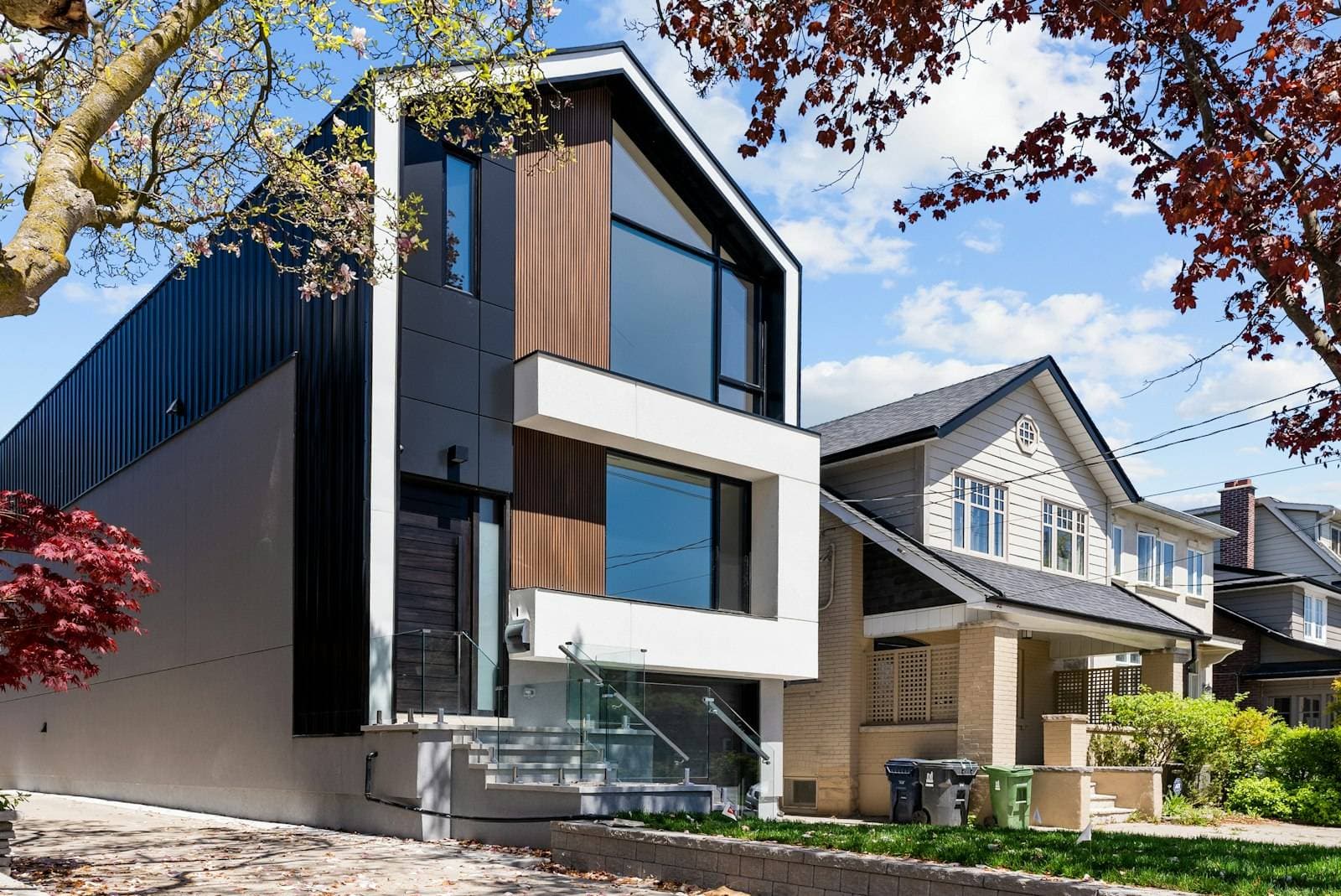 A crisp three-storey infill house in white render and dark timber between two traditional houses