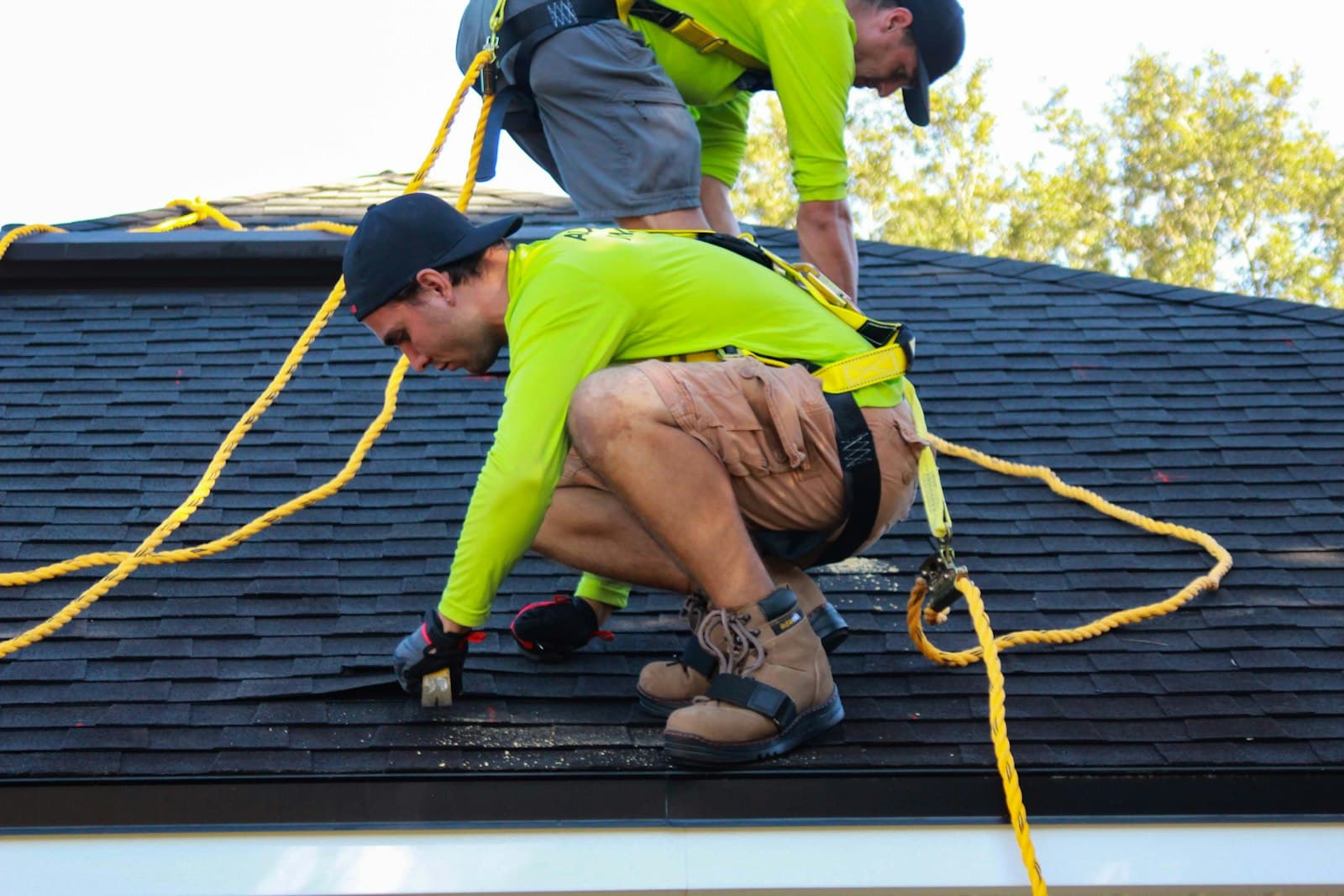 Two roofers in hi-vis and harnesses working across a pitched roof
