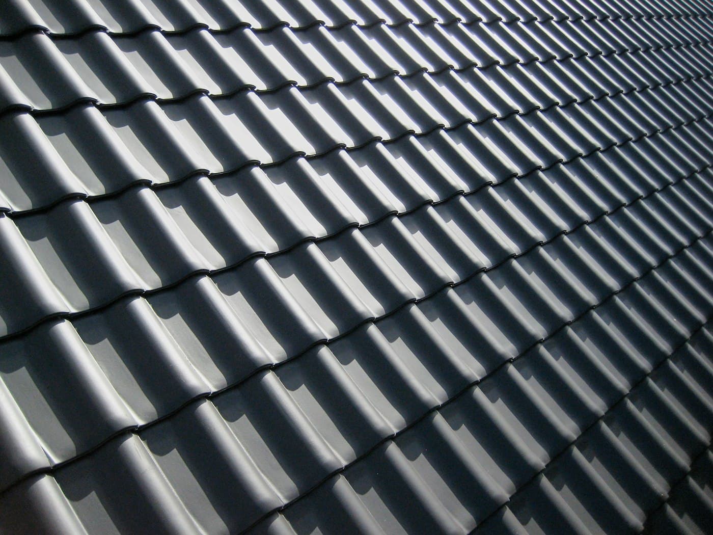 Close-up of dark grey interlocking roof tiles in raking light