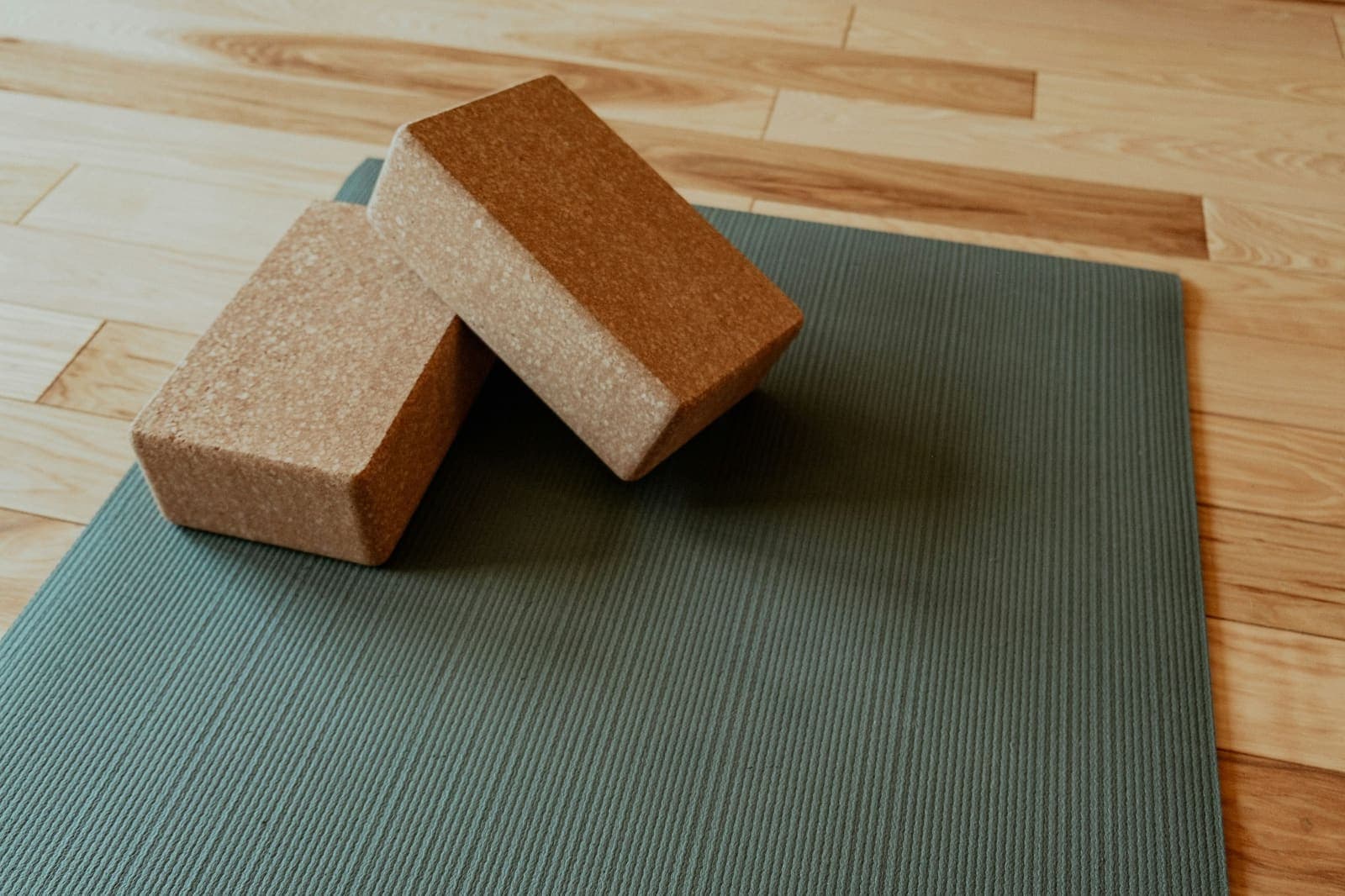 Two cork yoga blocks resting on a sage green mat