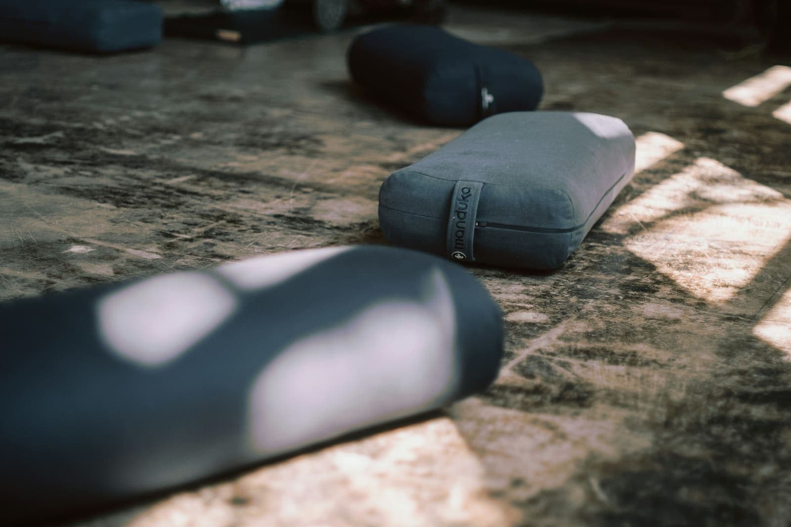 Round bolsters laid out on a studio floor in low afternoon light