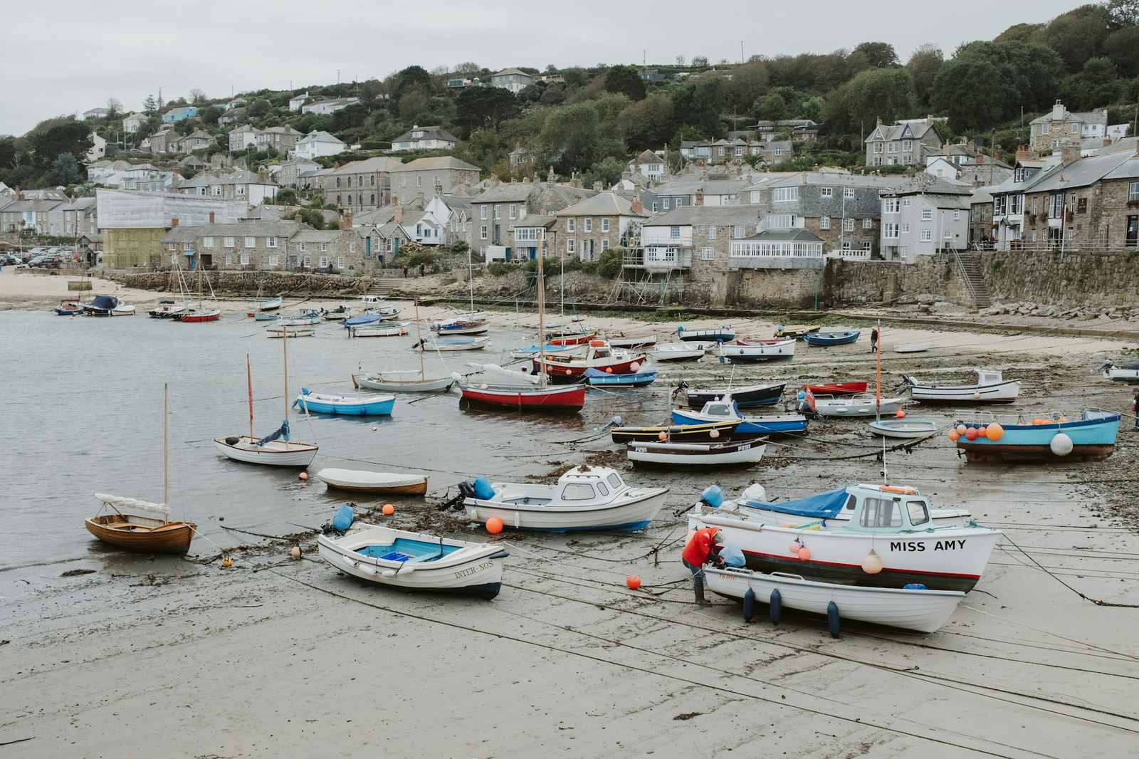 Boats resting on the sand at low tide in a Cornish harbour town