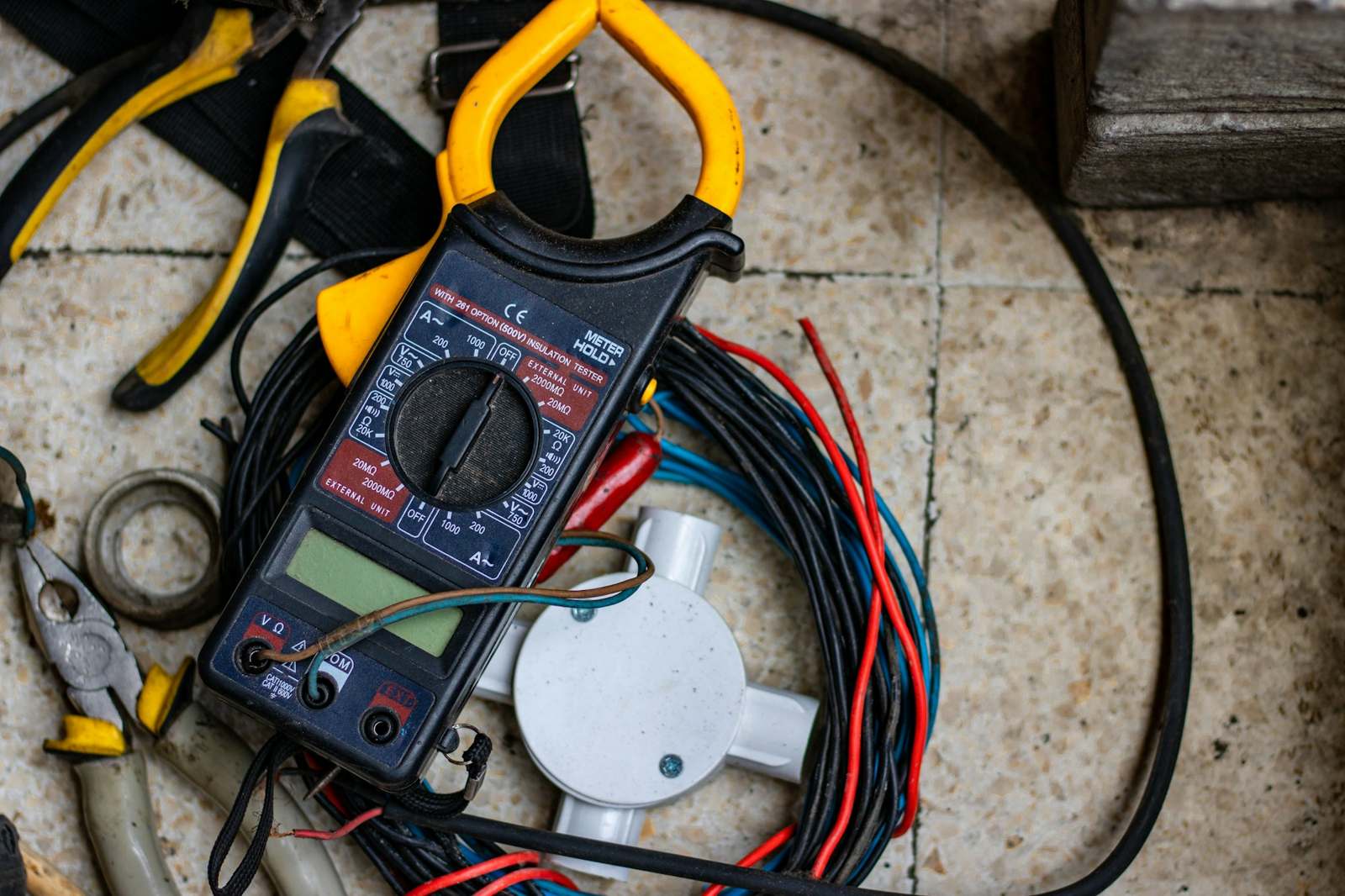 An electrician in gloves testing a circuit with a screwdriver probe